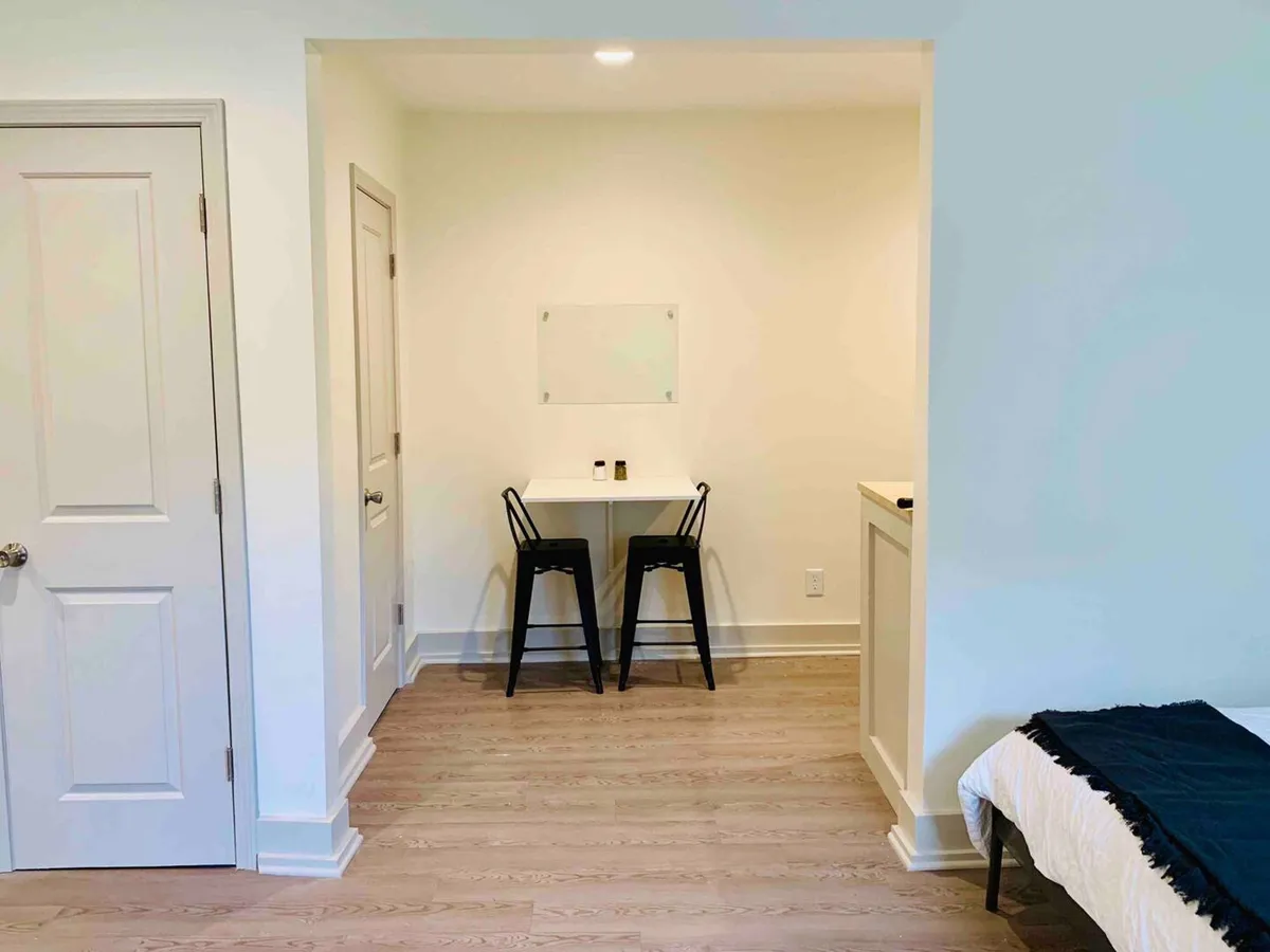 A multifunctional area that includes a table with two chairs, a bed, and a whiteboard. The space is cozy yet practical, perfect for dining, working, or relaxing in privacy.