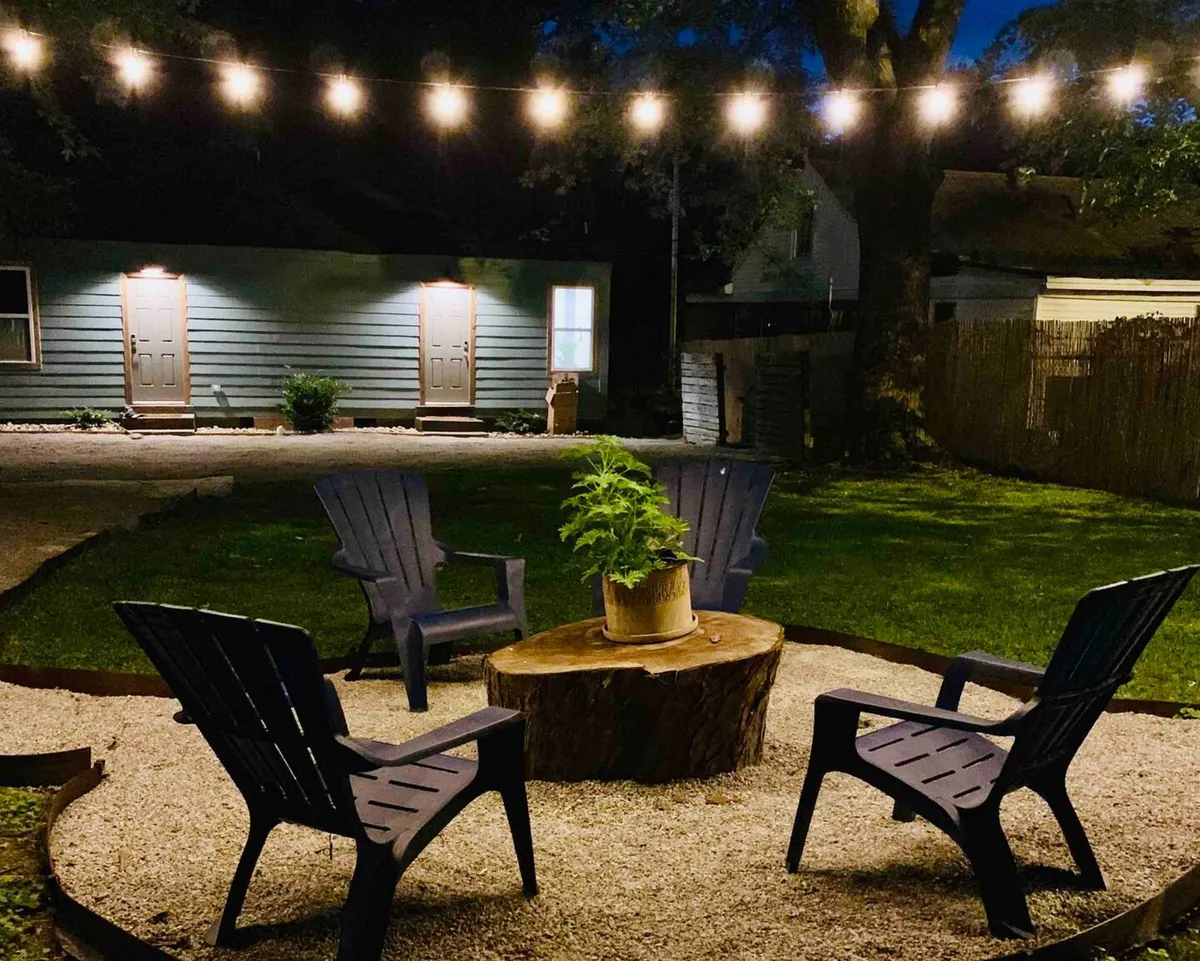 A relaxed and intimate backyard seating area illuminated with string lights, surrounding a fire pit and ample seating. The ambiance is perfect for unwinding after work, sharing drinks, and enjoying the outdoors, mirroring the section's mention of shaded backyard spaces ideal for relaxing after a day of meetings.